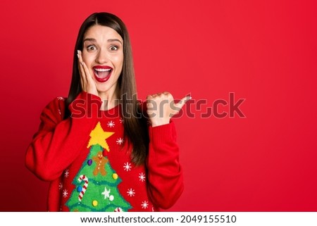 Photo of funny excited woman dressed ugly pullover arm cheek pointing thumb up empty space smiling isolated red color background