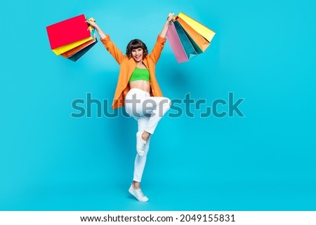 Full length photo of funny millennial brunette lady hold bags wear cardigan top jeans shoes isolated on teal background