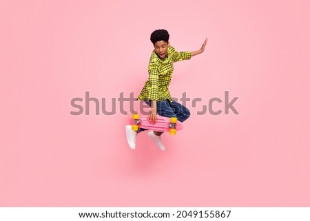 Full length photo of young funny brunette guy on board wear shirt jeans sneakers isolated on pink background