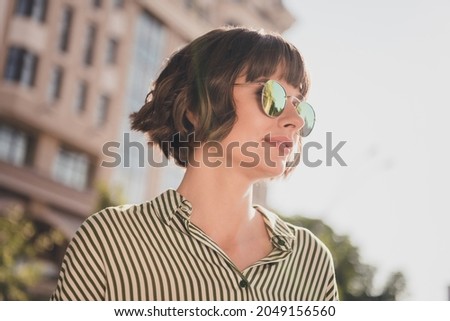 Photo portrait female student in striped shirt smiling wearing stylish sunglass walking on sunny city streets Royalty-Free Stock Photo #2049156560
