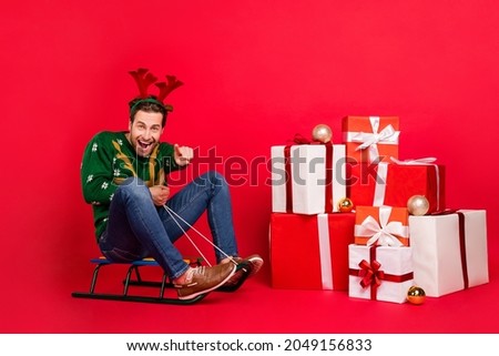 Full body photo of young guy happy smile ride sledge point finger you choose present isolated over red color background