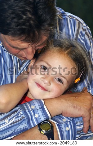 father takes daughter in his arms and gives her a kiss