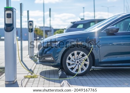 Electric car charging at a station in parking lot Royalty-Free Stock Photo #2049167765
