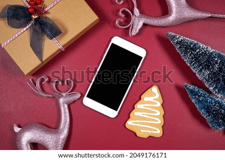 Smart phone product mockup. Christmas theme svg craft product mockup with pink reindeers, gift, gingerbread cookies and Xmas trees against a dark red magenta background.