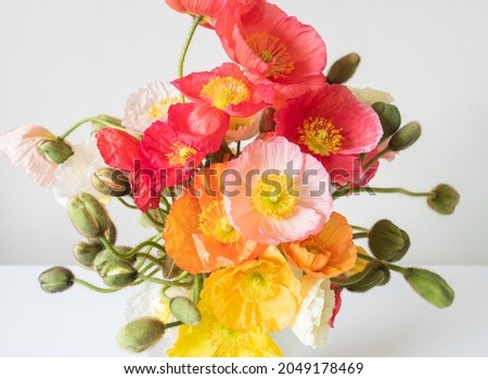 Close up of pink, orange and yelllow poppy flowers in vase from above (selective focus)