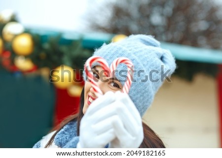 Happy brunette woman holding candies in a heart shape