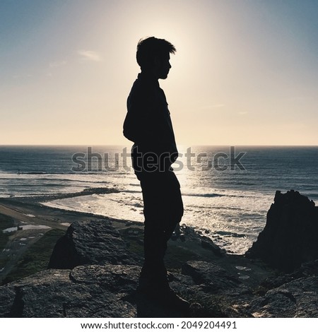 Silhouette of a young person standing on the beach in the sunset