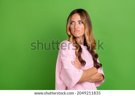 Photo of unhappy moody young lady wear pink shirt arms crossed looking back empty space isolated green color background