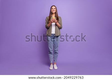 Full length body size photo smiling girl browsing internet with cellphone isolated pastel violet color background