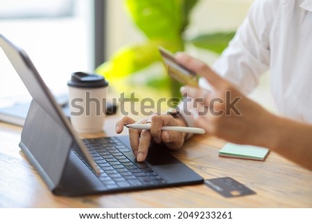 Close-up, Senior female using portable tablet to transfer money, holding credit card or business card