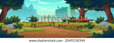 City park with wooden picnic table and benches, green trees, grass with flowers and town buildings on skyline. Vector cartoon summer landscape of empty public garden with food and drink on table Royalty-Free Stock Photo #2049258344