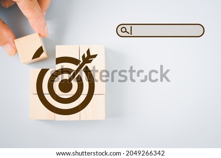 hand hold piece of wooden cube to complete dartboard icon shape with search bar beside, brainstorming for target or goal, find  the best method to reach target concept