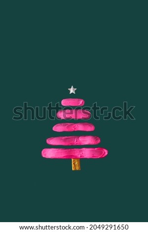 Neon pink color smeared on paper in the shape of a Christmas tree. Silver star on top. Green background. New Year concept.
