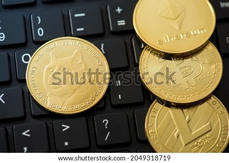 Closeup photo of gold coins with dogecoin ethereum bitcoin and litecoin symbols on black keyboard background