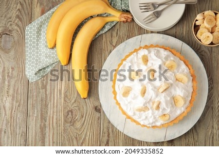 Board with tasty banana pie on wooden background Royalty-Free Stock Photo #2049335852