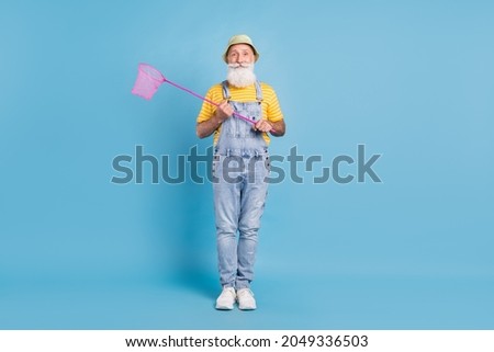 Full body photo of aged man happy positive smile hold net catch butterfly isolated over blue color background