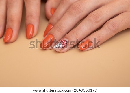 Female hands with orange manicure with a pattern under a glossy top. Creative idea for woman