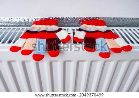 Bright knitted gloves drying on heating radiator