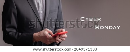 A businessman typing on a red cell phone near text - cyber Monday