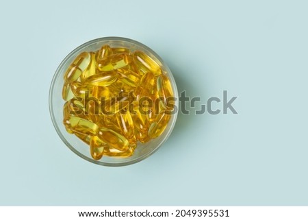 Fish oil omega 3 capsules lying in a bowl on a blue background