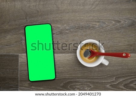Top view coffee cup looking at smartphone. Smartphone with green screen business concept