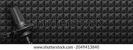 Recording studio microphone on black acoustic foam background with copy space. Podcast or broadcasting radio banner
