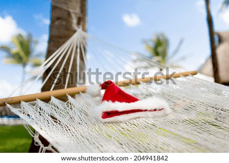 vacation, christmas and holiday concept - picture of hammock with santa helper hat