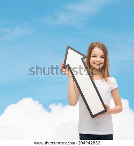 advertising and child concept - smiling little girl with blank arrow pointing up