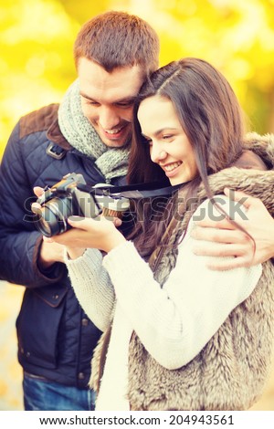 summer, holidays, vacation, travel, tourism, happy people, dating concept - couple with photo camera in autumn park