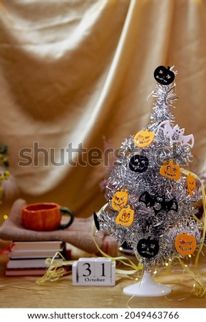 Trendy Halloween tree with festive decorations atmosphere. Halloween holidays with festive pumpkin cup and calendar. High quality photo