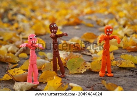 Funny colorful zombie figures on the background of autumn leaves.