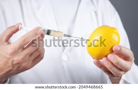 Doctor with syringe and lemon. Genetic modification