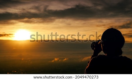 silhouette of  woman taking picture with camera at sunrise on DOI SUTHEP mountain viewpoint, chiang mai, Thailand