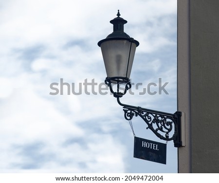 Zurich switzerland sept. 13 2021: old lantern with dirty hotel sign in front of blue sky and house facade, light blue colored picture, on day without people