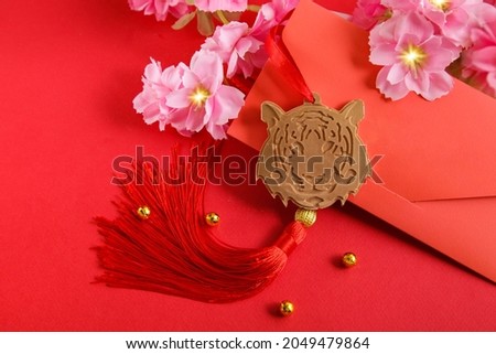 Chinese New Year 2022 decoration Gold Tiger, Red Envelope on red background. Flowers of good fortune. Royalty-Free Stock Photo #2049479864