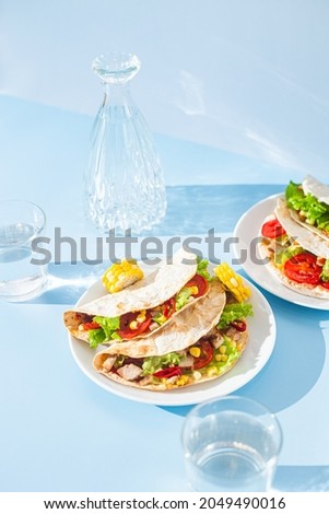 corn tortilla stuffed with meat and vegetables on a blue background. Taco