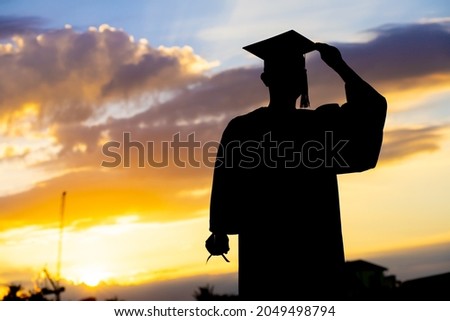 Silhouette Graduation Concept graduates holding certificates and cap on sky background
