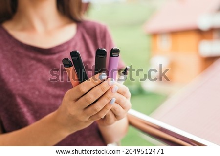 Many different disposable e-cigarettes in hand with delicious tastes Royalty-Free Stock Photo #2049512471