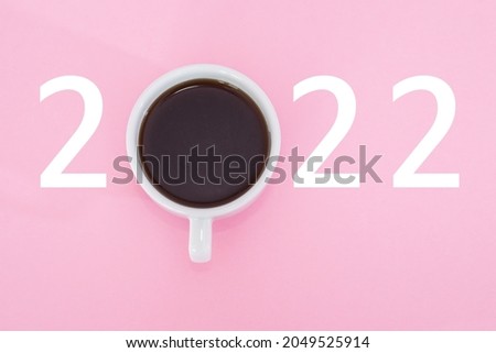Happy New Year 2022. Cup of coffee with number 2022 on pink background