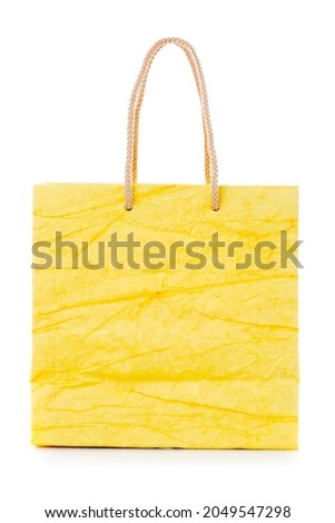 Yellow gift bag made of corrugated paper with raised handles. Consumer pack ready for logo design. Advertising and branding. Isolated on a white background.