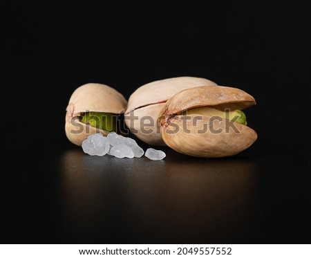 Delicious pistachios close-up with coarse salt. macro photography on a shiny black surface
