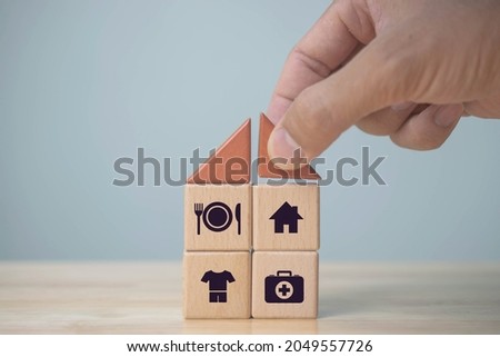 The investor's hand placed a wooden cube with word Work on wooden table. concept work from home, Planning to buy property concept ,food Clothing, housing, medicine, four basic human needs concept. Royalty-Free Stock Photo #2049557726