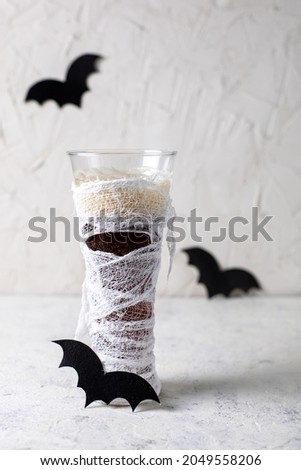 Glass of cocktail decorated as mummy. Drink for a halloween party for kids.