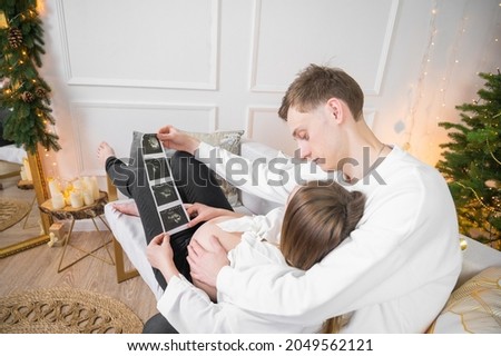 Pregnant woman showing an ultrasound image to her husband. A couple in love is expecting a baby.