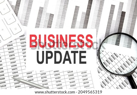 BUSINESS UPDATE text on the paper with calculator,magnifier ,pen on graph background