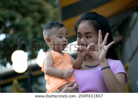 mother training baby doing ok and hello gesture