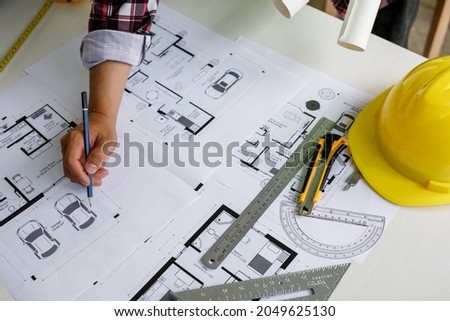 Architect design engineer working drawing sketch plans blueprints and making architectural construction model in a home office. Concept architects, Selective Focus