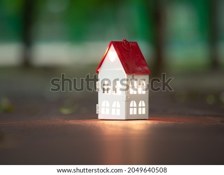 Home sweet home, house metal with inner glowing on dark night and blue background, with copy space.