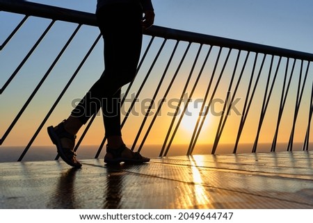 Unrecognizable woman legs walking on a bridge at dawn Royalty-Free Stock Photo #2049644747
