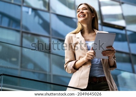Portrait of a successful business woman using digital tablet in front of modern business building Royalty-Free Stock Photo #2049645026